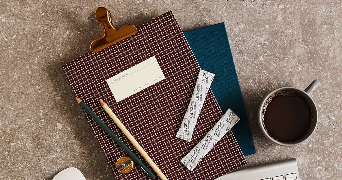 The Solution stick packs on a note book on a table beside a cup of coffee